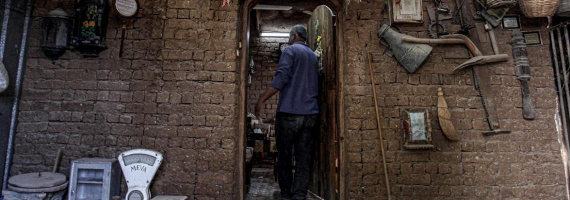 فلسطيني يرتب أثاثًا قديمة ومقتنيات في منزله الطيني بمدينة غزة