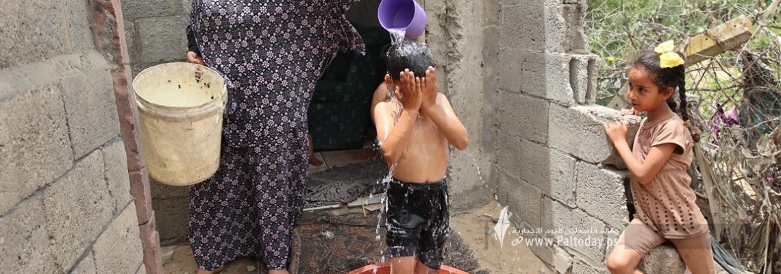 بالصور : أطفال غزة يواجهون ارتفاع درجة الحرارة  بـ طبق مياه بلاستيك