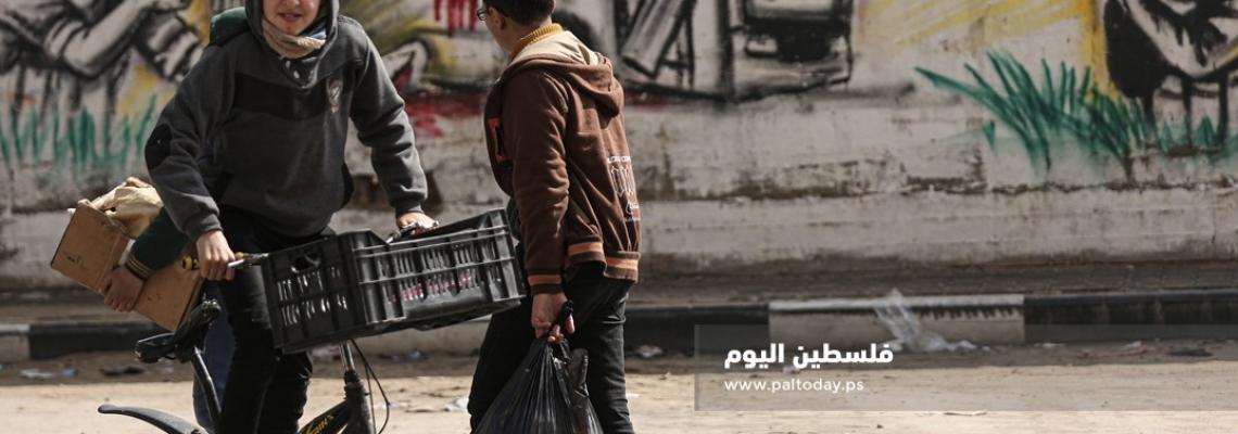 أشبال يمرون من أمام لوحة مرسومة للمقاومة والباص المتفجر على أحد شوارع مدينة غزة