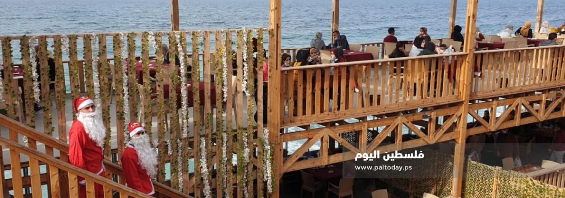 فلسطينيان يرتديان "بابا نويل" اثناء عملهما في احدى المقاهي بغزة