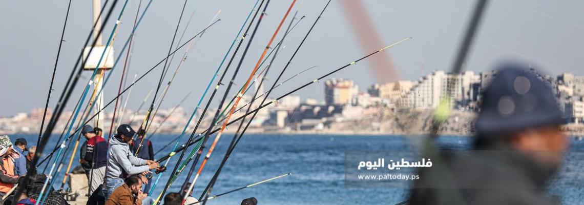 فلسطينيون يمارسون الصيد بالصنارة في ميناء غزة البحري