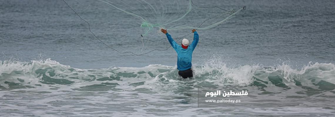 فلسطيني أثناء ممارسة مهنة الصيد في الأجواء البادرة على شاطئ غزة