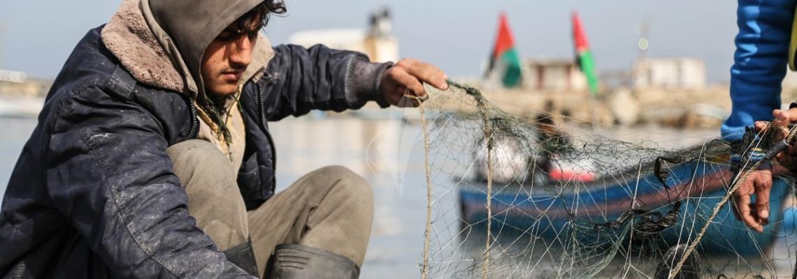 بالصور: صياد فلسطينى يقوم بغزل شباك الصيد بميناء غزة