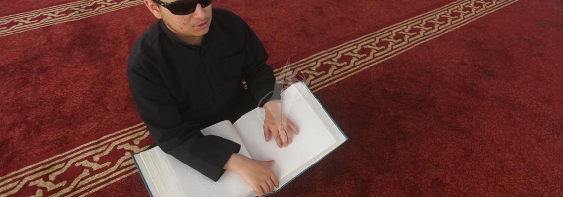 بالصور: طفل فلسطيني مكفوف داخل احد مساجد قطاع غزة يتعلم قراءة القران الكريم