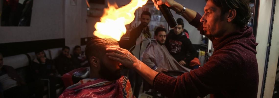 بالصور:غزّي يستخدم النار في حلاقة شعر الزبائن