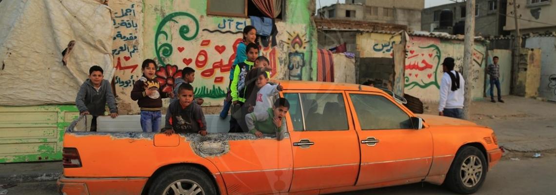 أطفال فلسطينيون يجلسون على خلفية سيارة أجرة من 6 أبواب في سيارة مرسيدس تم تحويلها إلى سيارة بيك آب في مخيم الشاطئ للاجئين