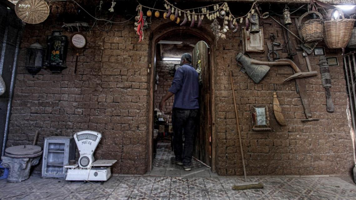 فلسطيني يرتب أثاثًا قديمة ومقتنيات في منزله الطيني بمدينة غزة