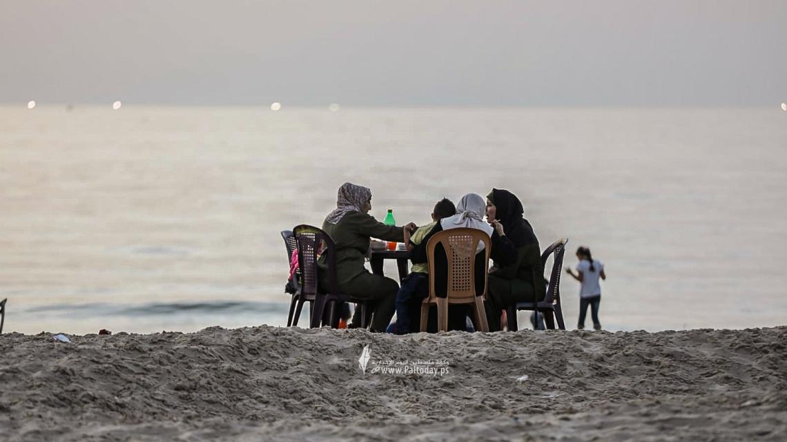 عائلات فلسطينية تتناول طعام الإفطار الرمضاني على شاطئ بحر غزة، بعد إلغاء حظر التجول.