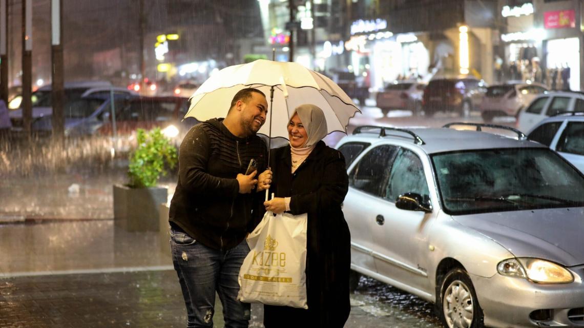 تحت زخات المطر.. مواطنون يتجولون في حي الرمال وسط مدينة غزة مساء اليوم