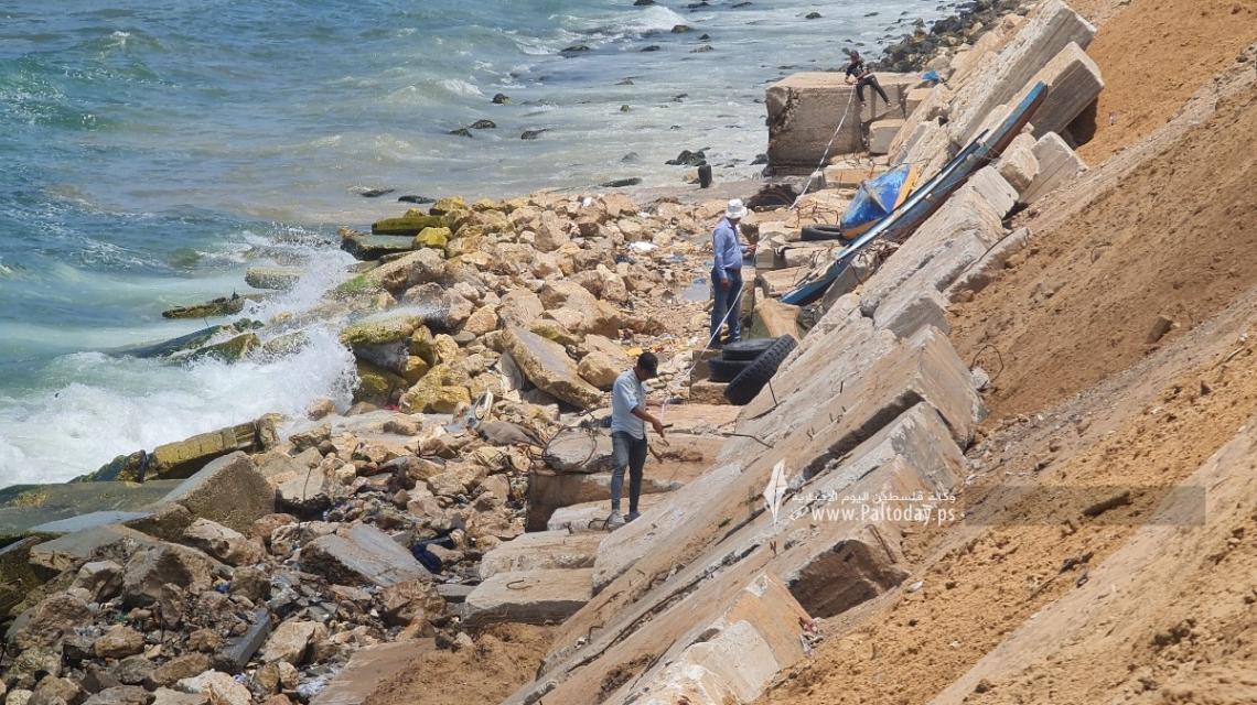 بالصور: عمال بناء فلسطينيون يبنون جدارًا بحريًا ، من أنقاض المباني المدمرة لمنع  تآكل الساحل بالقرب من مخيم الشاطئ