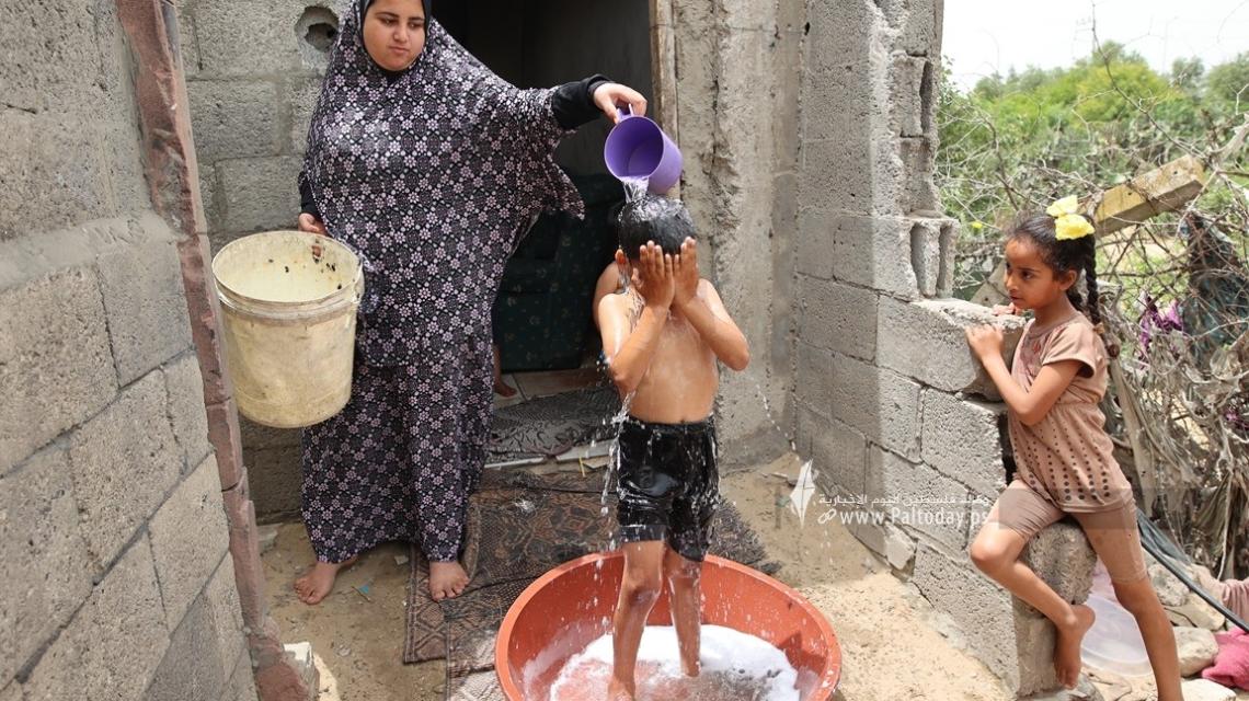 بالصور : أطفال غزة يواجهون ارتفاع درجة الحرارة  بـ طبق مياه بلاستيك