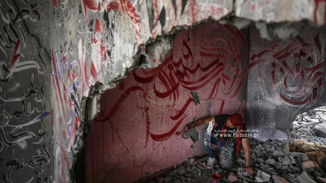بالصور : الفنان الفلسطيني أيمن الحصري يرسم جدرايات بالخط العربي على أحد المنازل التي دمرت بفعل قصف الاحتلال في بيت لاهيا شمال قطاع غزة