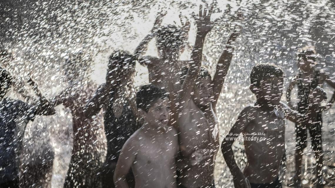 أطفال إحدى القرى النائية في قطاع غزة يخففون عن أنفسهم حرارة الجو في مسبح بالشارع .