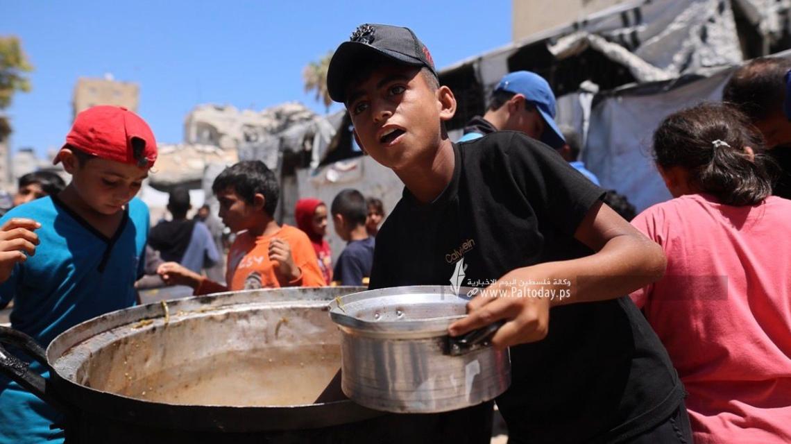 مواطنون يتجمعون أمام مطبخ خيري بانتظار استلام وجبات الطعام، في غرب مدينة غزة، في ظل استمرار الأزمة الإنسانية ونقص المواد الغذائية