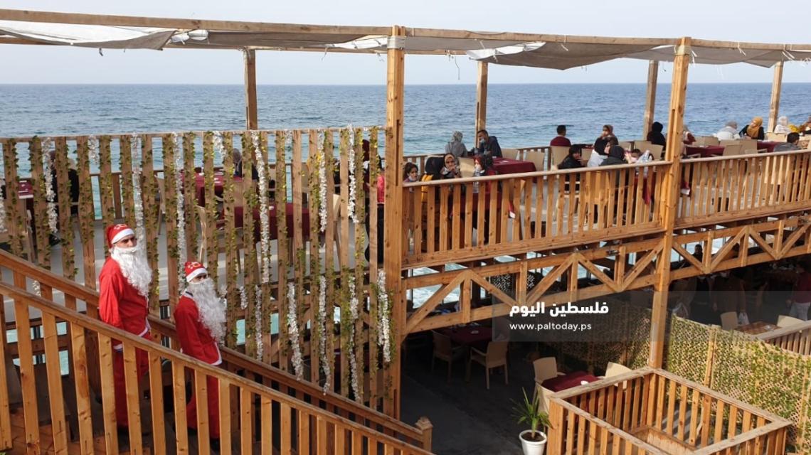 فلسطينيان يرتديان "بابا نويل" اثناء عملهما في احدى المقاهي بغزة