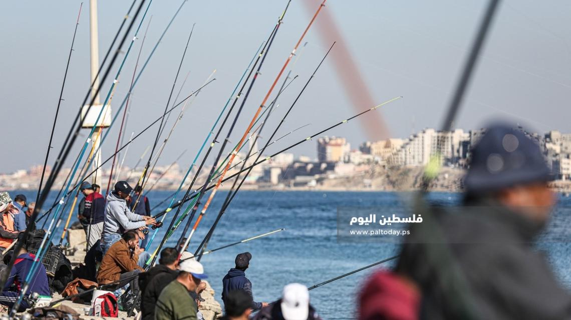 فلسطينيون يمارسون الصيد بالصنارة في ميناء غزة البحري