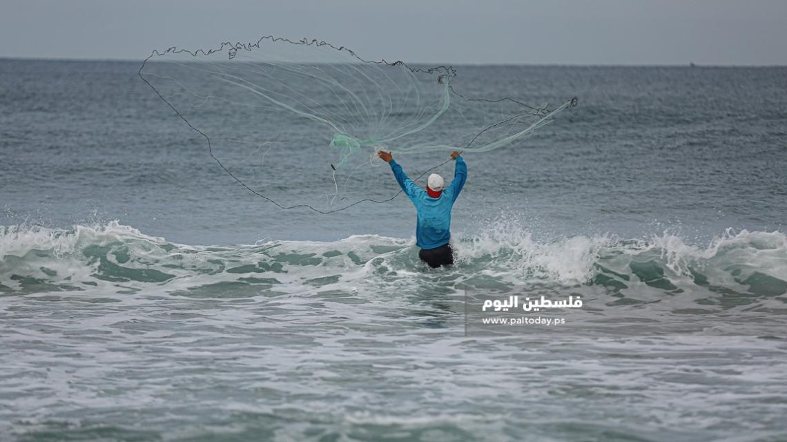 فلسطيني أثناء ممارسة مهنة الصيد في الأجواء البادرة على شاطئ غزة