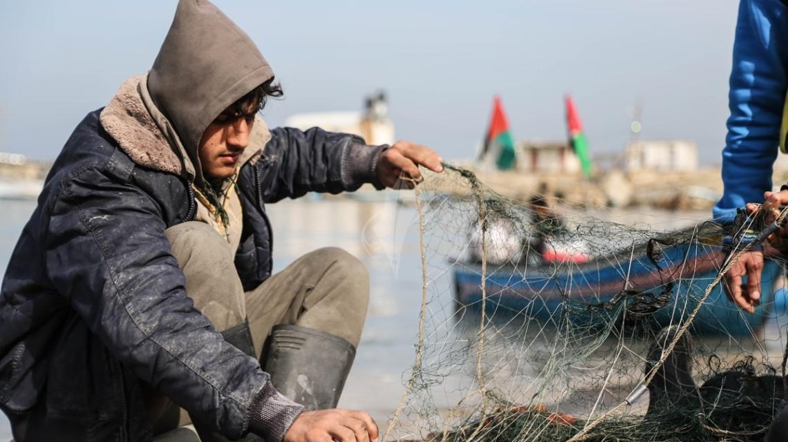 بالصور: صياد فلسطينى يقوم بغزل شباك الصيد بميناء غزة