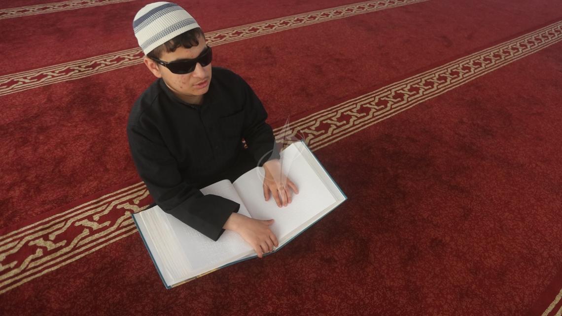 بالصور: طفل فلسطيني مكفوف داخل احد مساجد قطاع غزة يتعلم قراءة القران الكريم