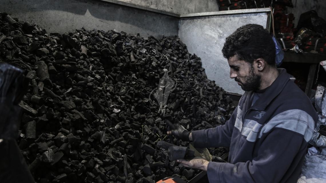 بالصور:عمال فلسطينيون يُعيدون تعبئة الفحم المستورد من مصر في أكياس صغيرة ليتم بيعه بسعر 6 شيكل للكيلو