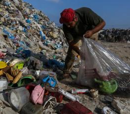 شاب يجمع البلاستيك من إحدى مكبات النفايات في غزة