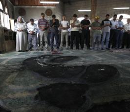 بالصور : مصلون فلسطينيون يؤدون الصلاة داخل مسجد تم حرقة من قبل المستوطنين