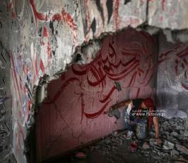 الفنان الفلسطيني أيمن الحصري يرسم جدرايات بالخط العربي على أحد المنازل التي دمرت بفعل قصف الاحتل (1)