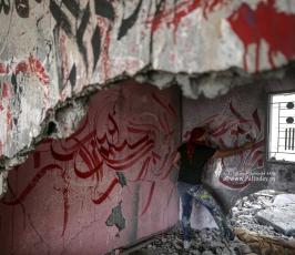 الفنان الفلسطيني أيمن الحصري يرسم جدرايات بالخط العربي على أحد المنازل التي دمرت بفعل قصف الاح (4)