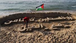 فلسطيني يكتب بالخط العربي على رمال شاطئ بحر غزة