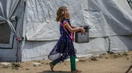 طفلة فلسطينية من غزة تحمل وعاء تأمل أن تملؤه بالطعام