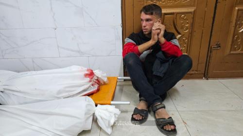 مواطن يجلس بجانب شهداء في غزة