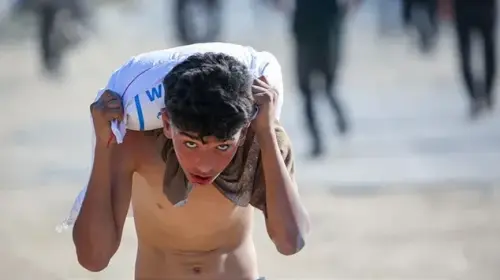 طفل من غزة يحمل كيس طحين في وقت المجاعة