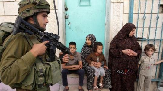 جندي صهيوني يشهر سلاحه بوجه عائلة فلسطينية