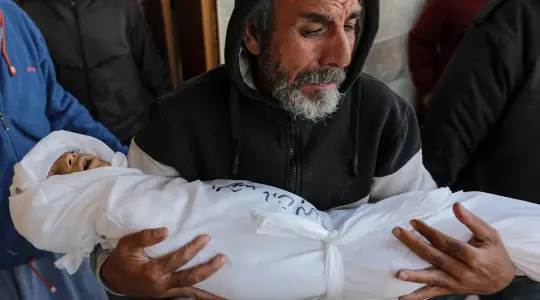 صورة لأب يشيع أحد أبناءه لمثواه الأخير في قطاع غزة
