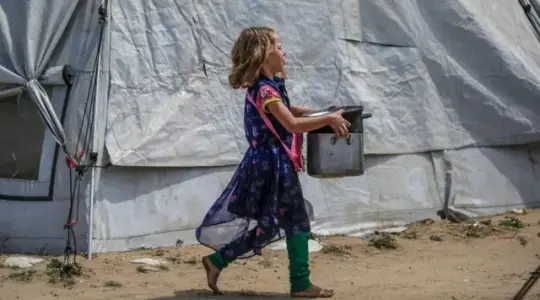 طفلة فلسطينية من غزة تحمل وعاء تأمل أن تملؤه بالطعام