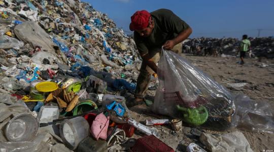 شاب يجمع البلاستيك من إحدى مكبات النفايات في غزة