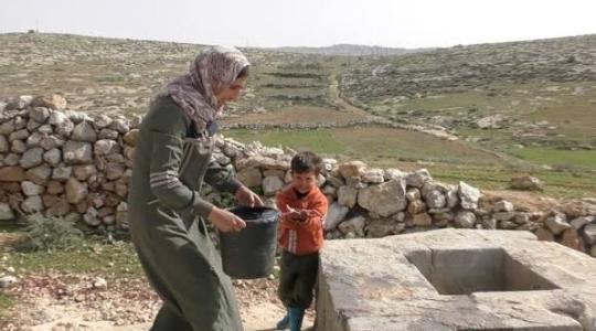 إمرأة تحمل وعاءً لتعبئته ماء للشرب.jpeg