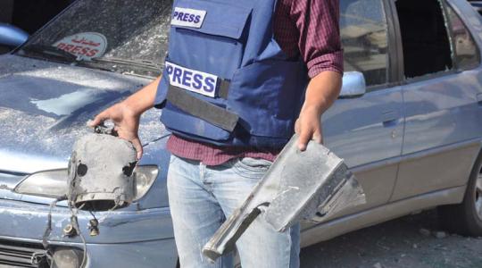 صحافي يحمل بقايا صاروخ إسرائيلي استهدف زملائه بغزة