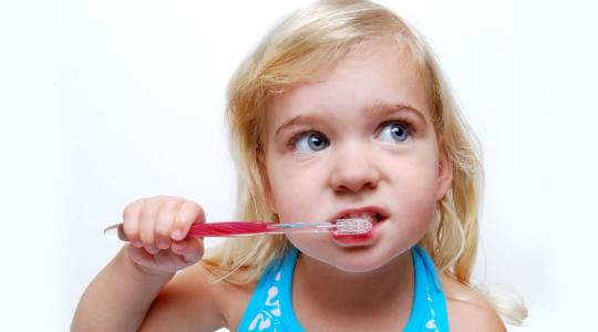 طفلة تقوم بفرشاة أسنانها
