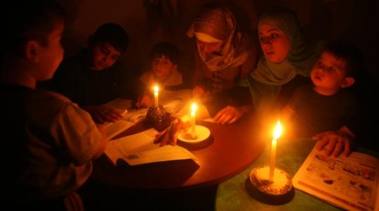 عائلة فلسطينية تتجمهر حول الشمع في ظل ازمة الكهرباء