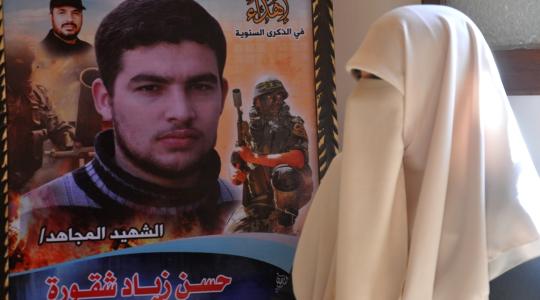 والدة الشهيد حسن شقورة بجوار صورة نجلها