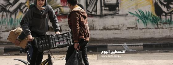 أشبال يمرون من أمام لوحة مرسومة للمقاومة والباص المتفجر على أحد شوارع مدينة غزة