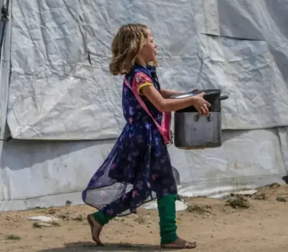 طفلة فلسطينية من غزة تحمل وعاء تأمل أن تملؤه بالطعام