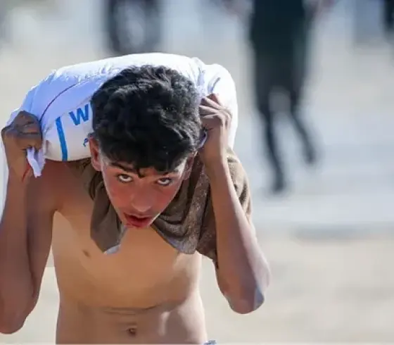 طفل من غزة يحمل كيس طحين في وقت المجاعة