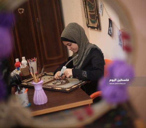هلا ابو قاعود خلال تصميمها لإحدى اللوحات