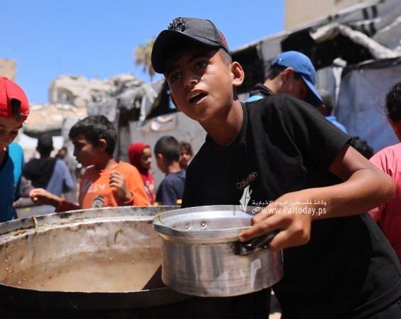 مواطنون يتجمعون أمام مطبخ خيري بانتظار استلام وجبات الطعام، في غرب مدينة غزة، في ظل استمرار الأزمة الإنسانية ونقص المواد الغذائية
