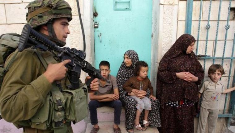 جندي صهيوني يشهر سلاحه بوجه عائلة فلسطينية