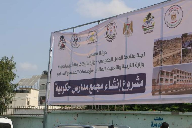 رفع لافتة أمام مقبرة (التوانسي) في الشجاعية لمشروع إنشاء مجممع مدارس حكومية