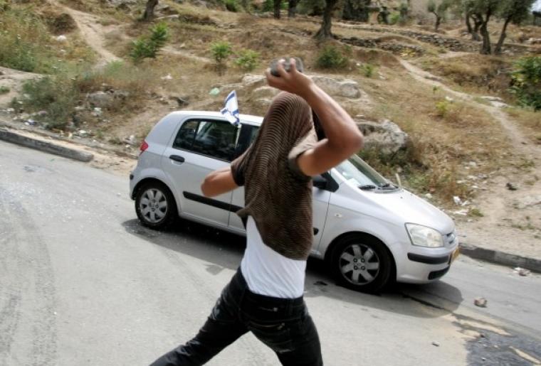 شاب يرشق مركبة مستوطن بالحجارة في الضفة الغربية المحتلة (أرشيفية)
