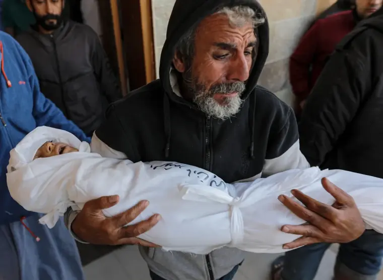 صورة لأب يشيع أحد أبناءه لمثواه الأخير في قطاع غزة